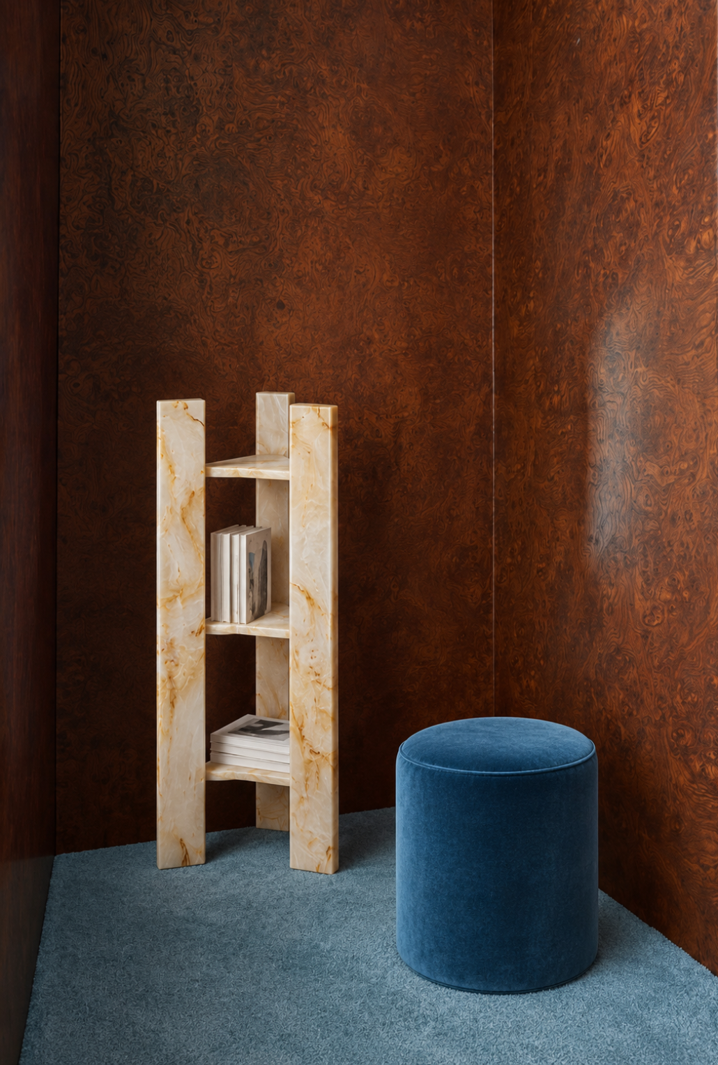 TRIGONUS freestanding bookcase in Italian yellow onyx with books beside a blue ottoman, Studio IB Milano