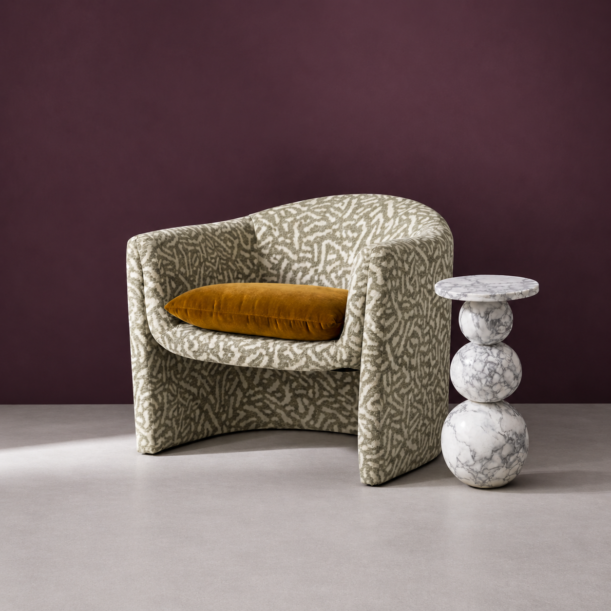 Carved marble side table with spherical base beside a patterned armchair by Studio IB Milano